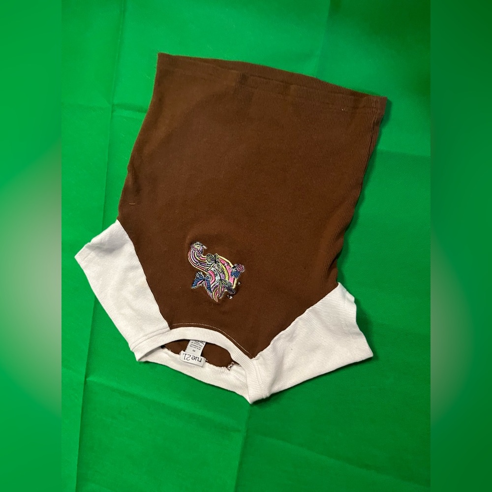 brown shirt with a small figure in the middle of a small rainbow and butterfly